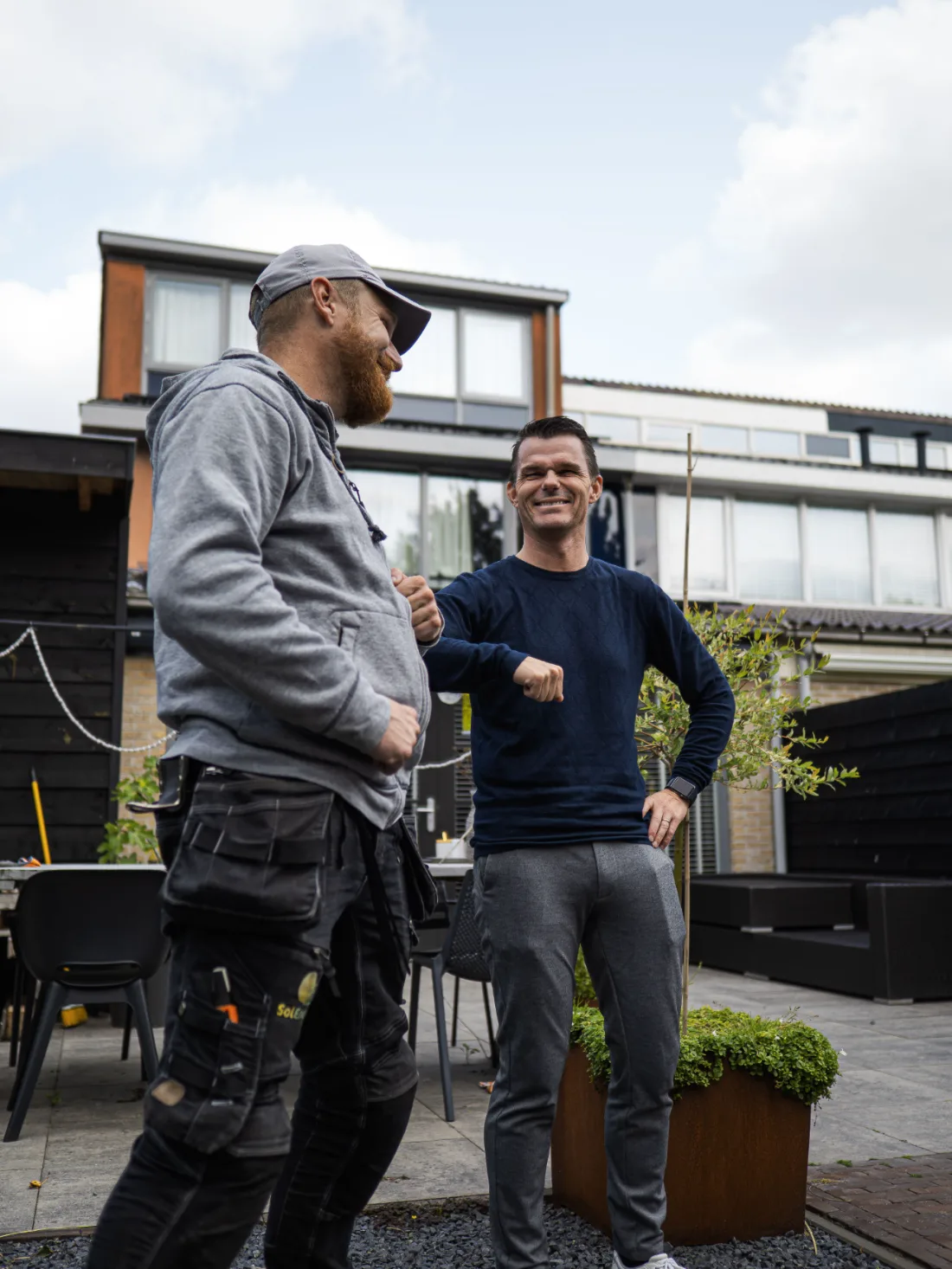 Klant en monteur geven elkaar een boks in de achtertuin na de installatie